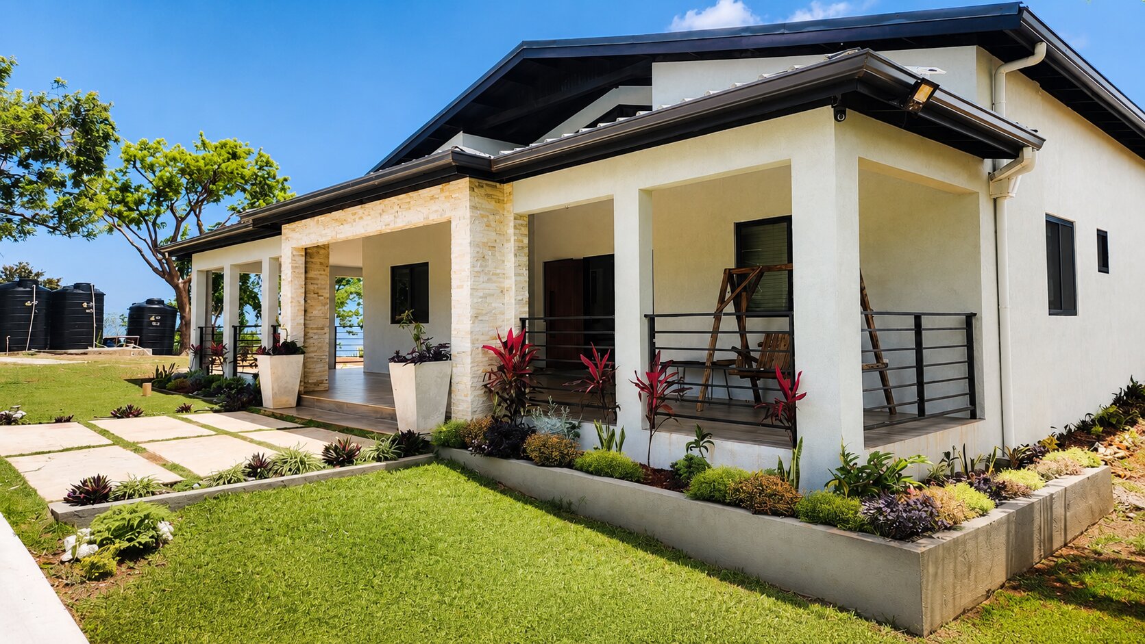 James Pointe Villa exterior, a single-storey hillside home with a covered veranda, stone columns and a manicured lawn