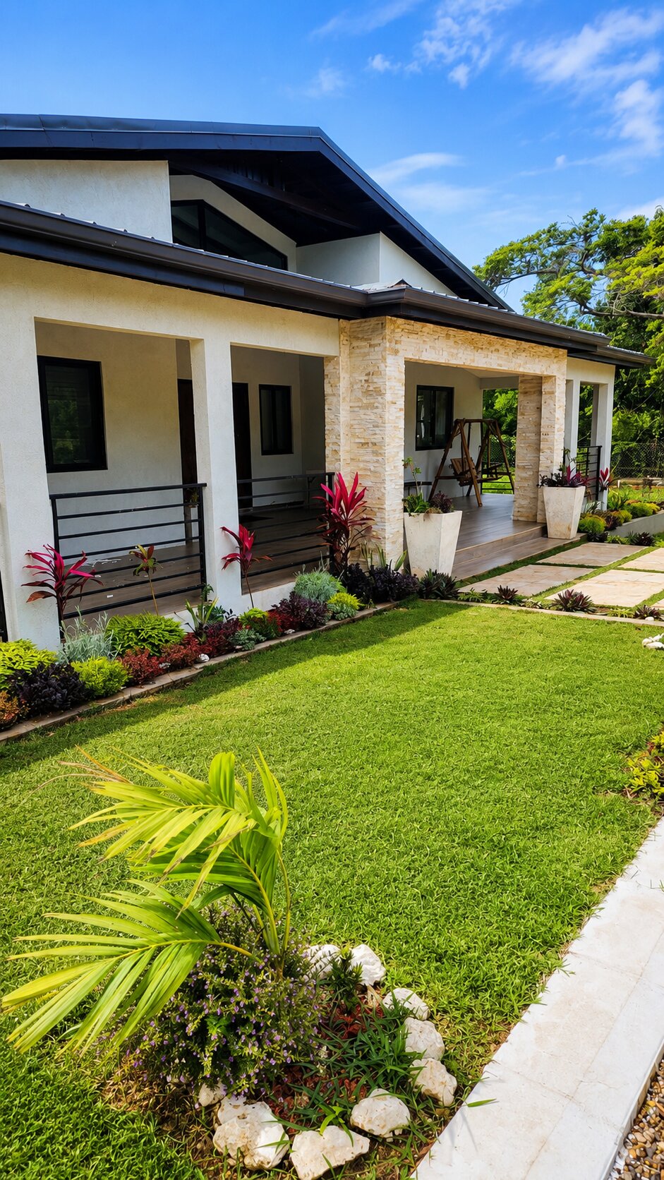 The villa's covered veranda, stone columns and landscaped front garden