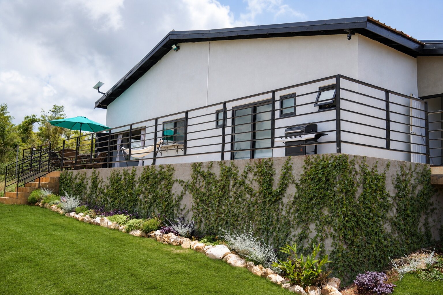 The raised back deck with a hammock, BBQ grill and teal umbrella