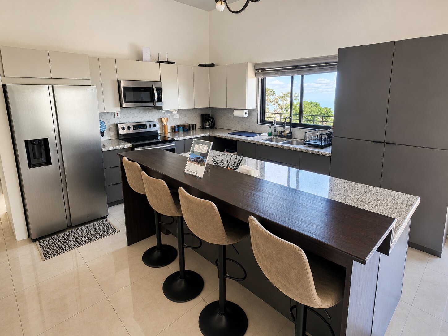 The kitchen with a granite breakfast bar, stainless appliances and an ocean-view window