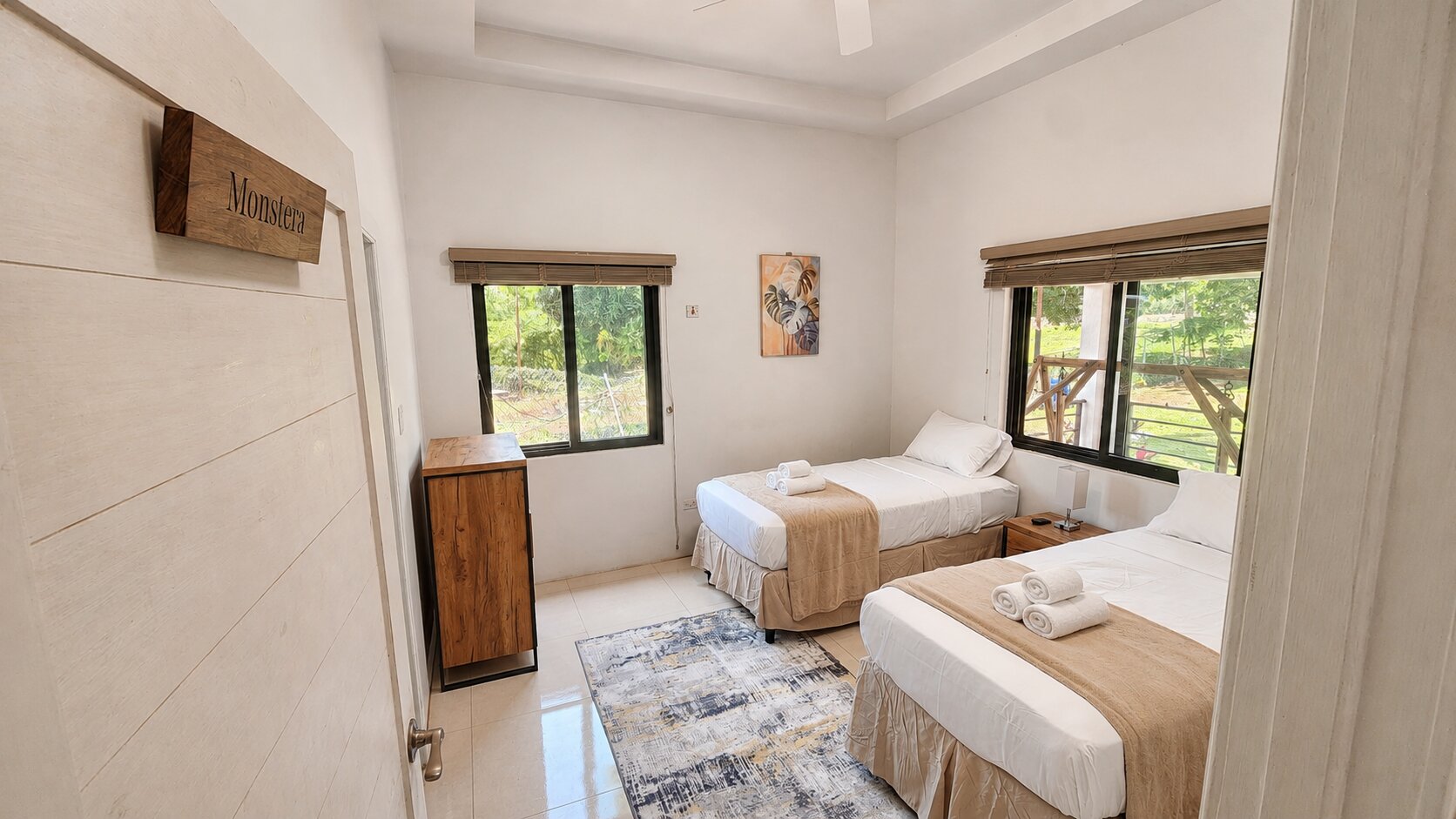 The Monstera bedroom with two twin beds, garden-view windows and monstera artwork
